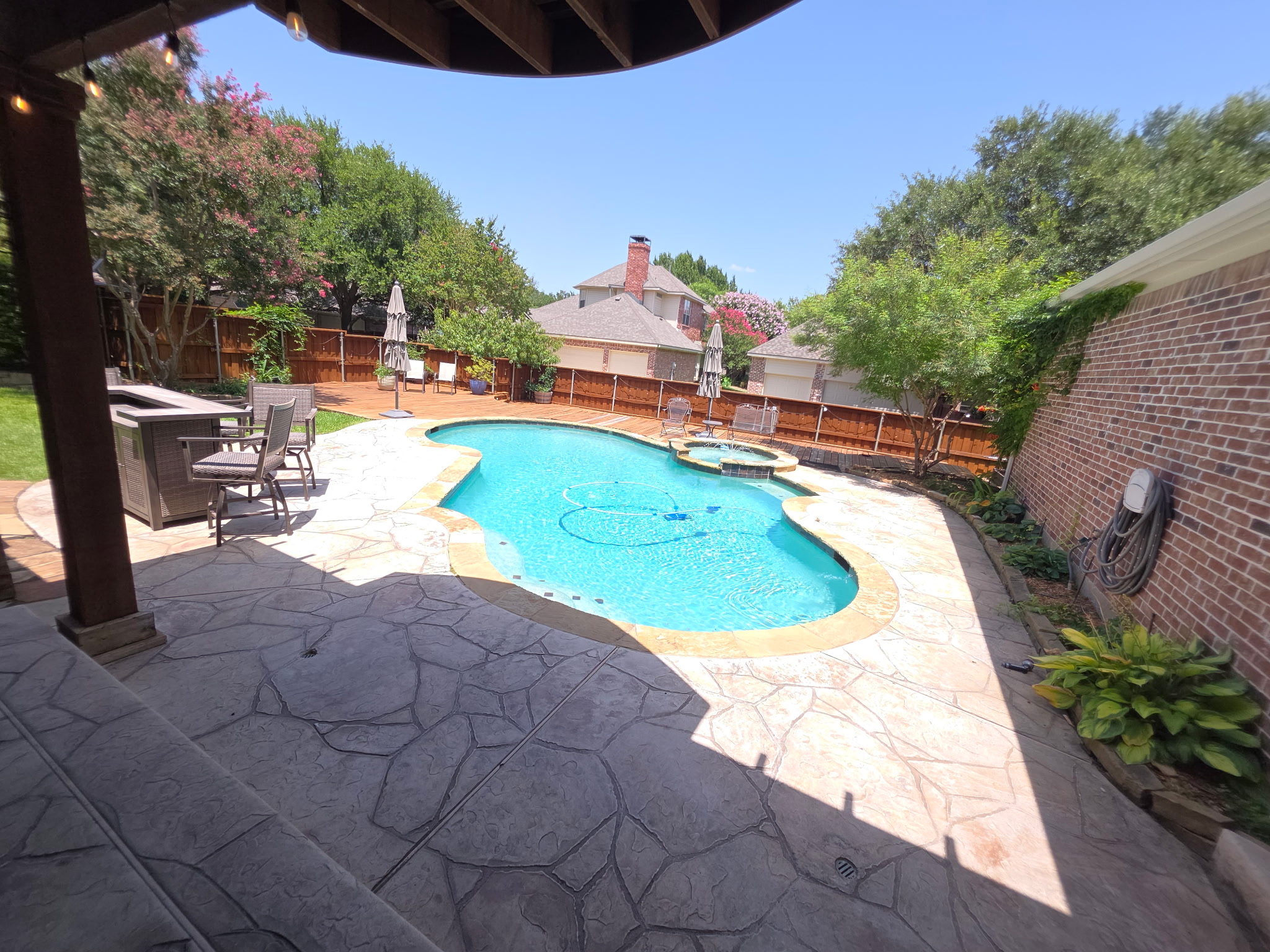 Freeform pool with outdoor kitchen and stamped concrete patio, Frisco TX