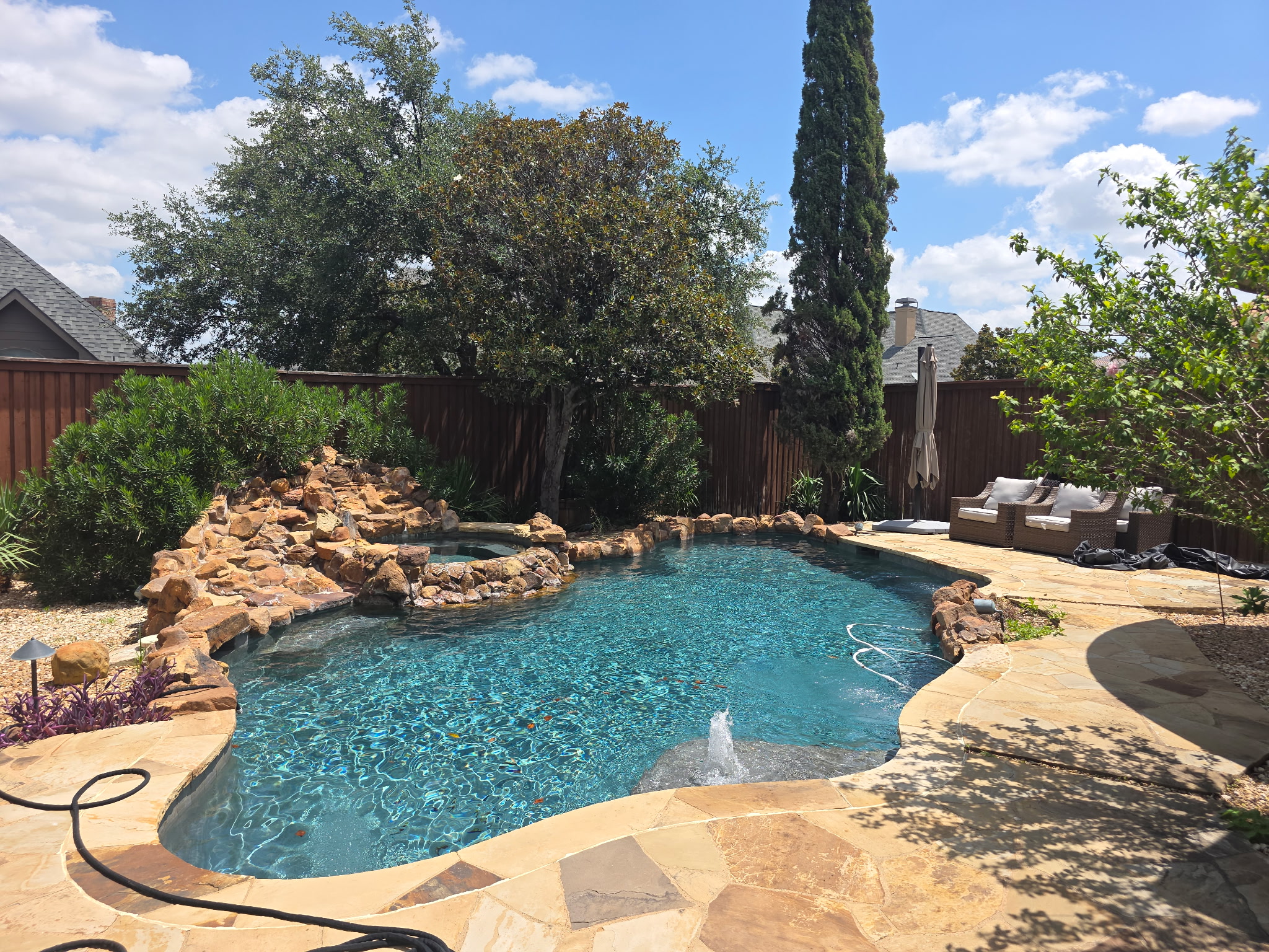 Freeform backyard pool with rock waterfall serviced by Crimson Pool Service in DFW